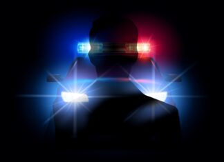 a silhouette of a police officer with his lights on