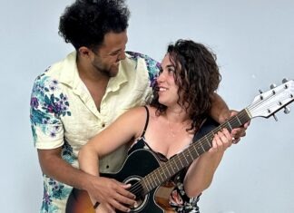 a man holding a guitar next to a woman