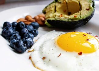 a white plate topped with an egg, blueberries and avocado