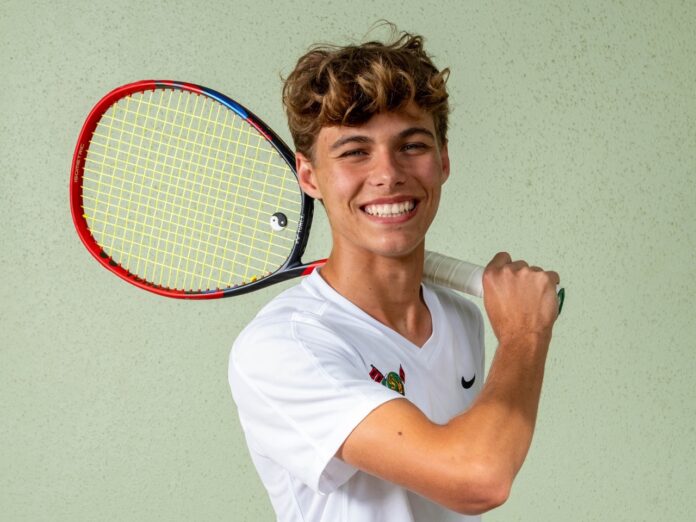 a young man holding a tennis racquet on a tennis court