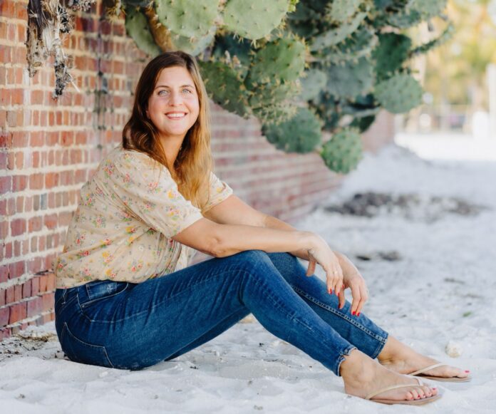 a woman sitting on the ground in front of a brick wall