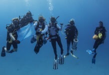 a group of scuba divers holding a blue flag