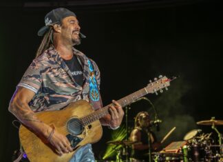 a man with dreadlocks playing a guitar on stage