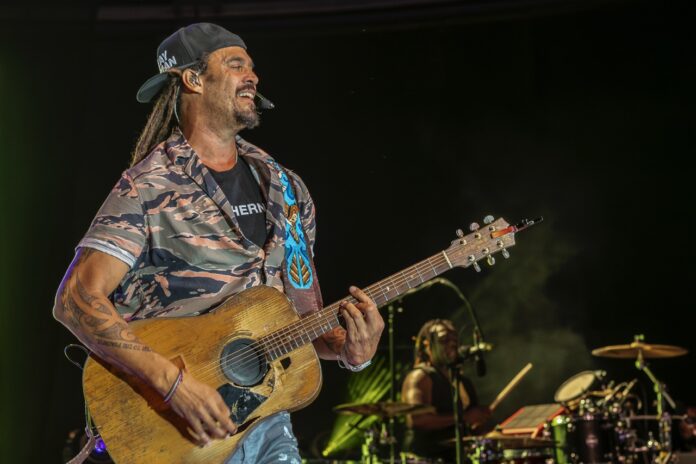 a man with dreadlocks playing a guitar on stage