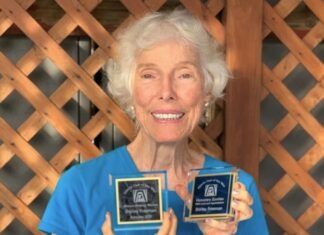 an older woman holding two plaques in her hands