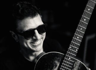 a man wearing sunglasses holding a guitar