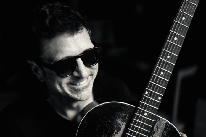 a man wearing sunglasses holding a guitar