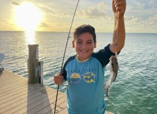 a young boy holding a fish on a dock