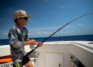 a young boy fishing on a boat in the ocean
