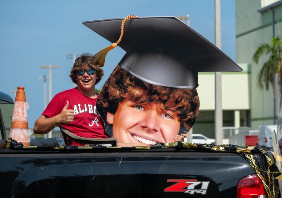 a man in a graduation cap sitting in the back of a truck