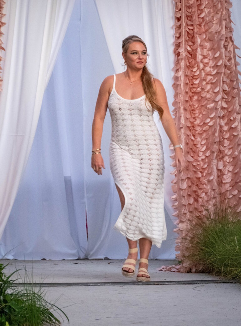 a woman in a white dress walking down a runway