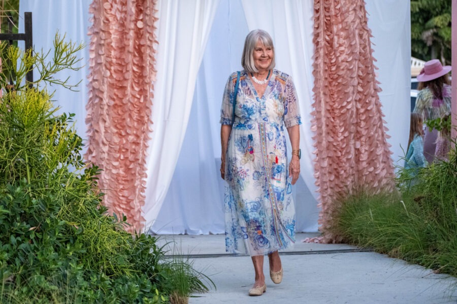 a woman standing in front of a white and pink curtain