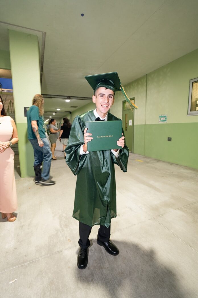 a man in a graduation gown holding a diploma