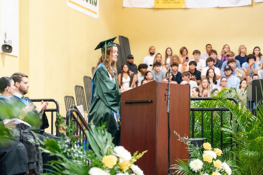 a graduate standing at a podium in front of a crowd