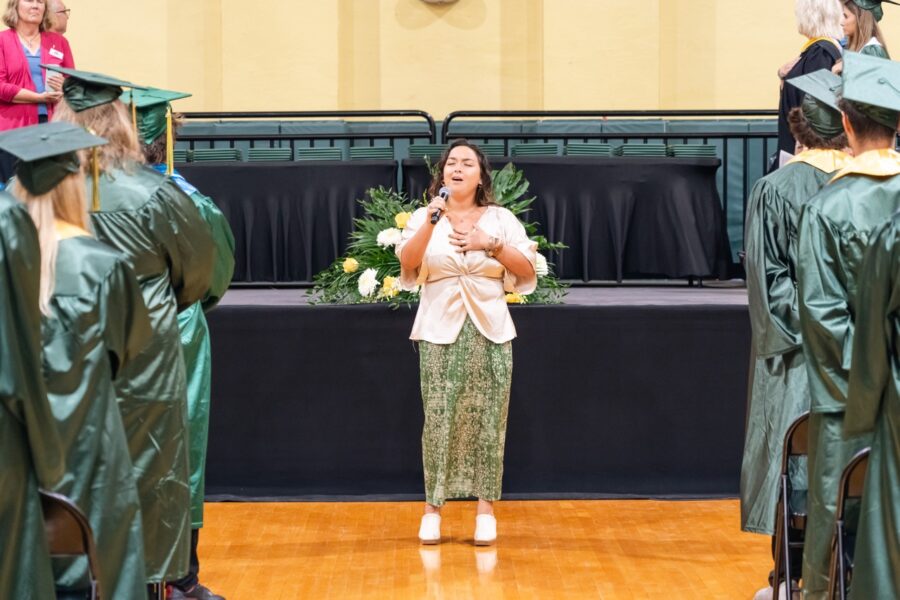 a woman standing in front of a group of graduates