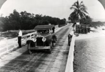 a vintage photo of an old car on a bridge