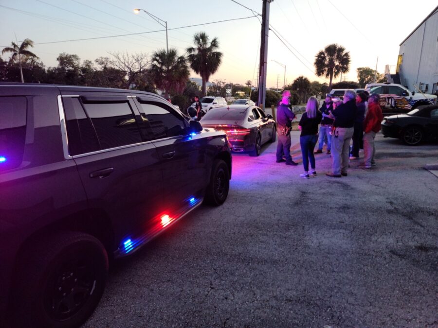 a group of people standing next to a police car