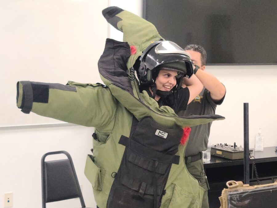 a man in a green jacket is holding a helmet on his head
