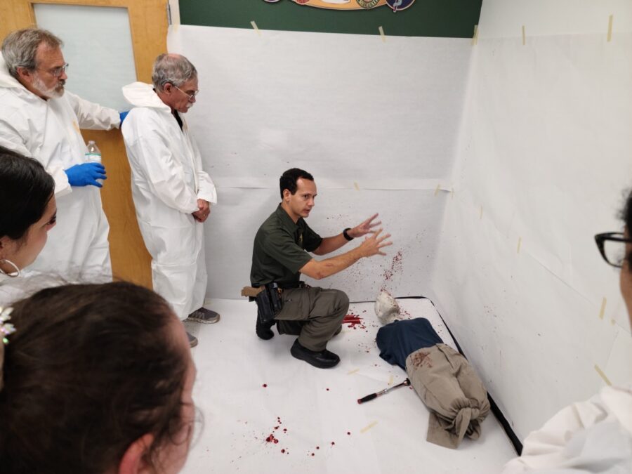 a group of people in white lab coats standing around a man laying on the floor