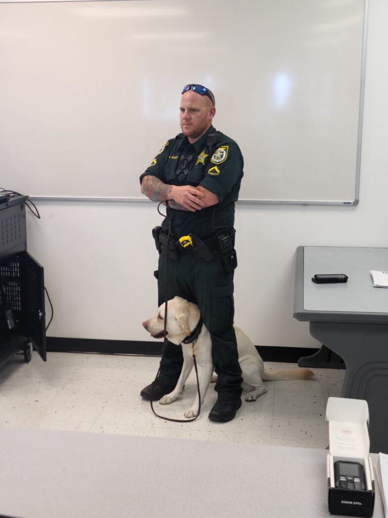 a police officer standing next to a dog