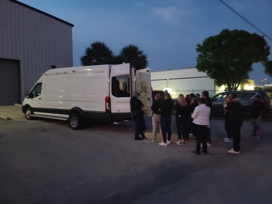 a group of people standing around a white van