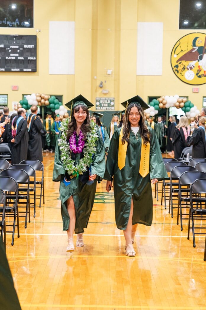 two graduates walk down the hall at graduation