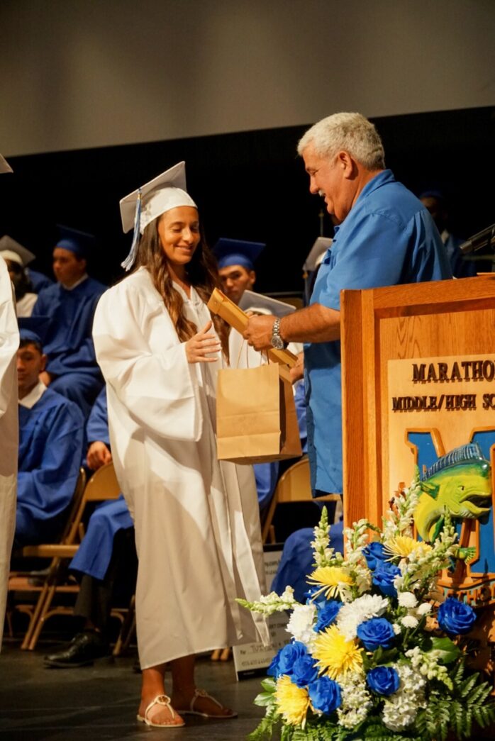 a woman in a graduation gown shaking hands with a man