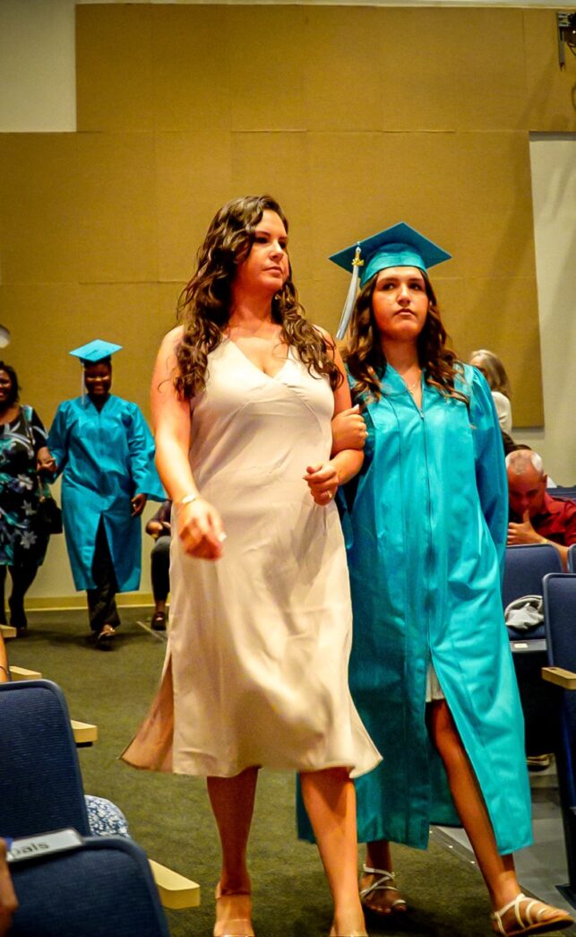 a group of women in graduation gowns walking down a hall