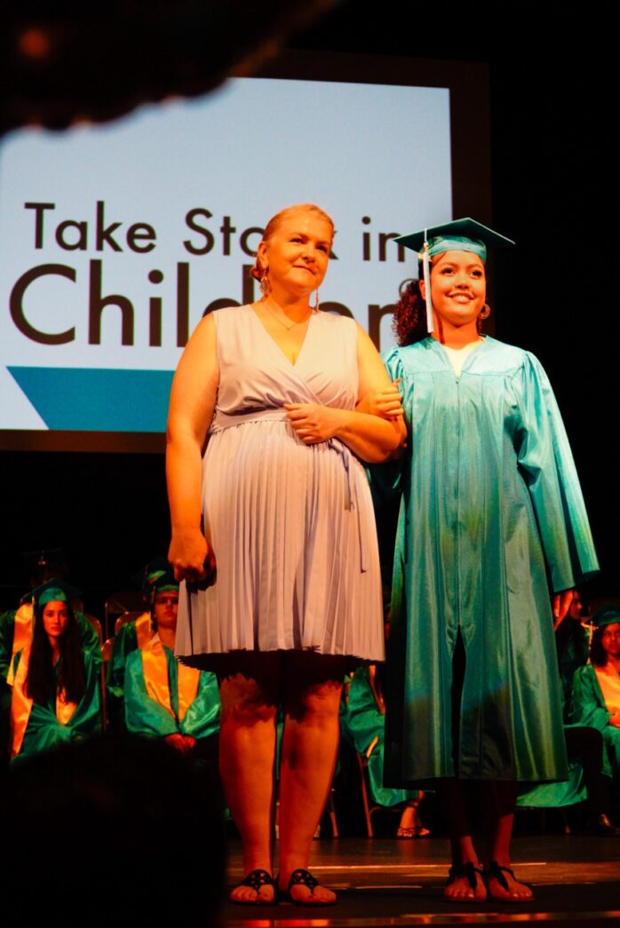 a woman standing next to a woman in a graduation gown