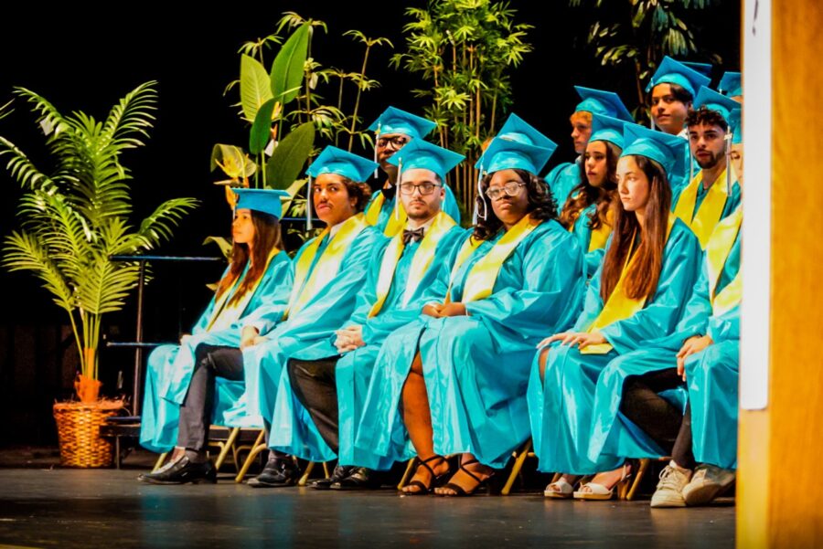 a group of people in graduation gowns sitting on a stage