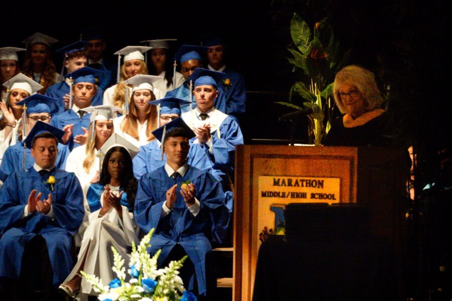 a group of people in graduation gowns sitting on a stage