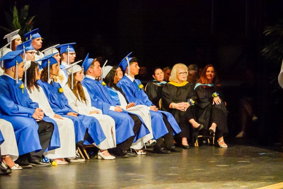 a group of people in graduation gowns sitting on a stage