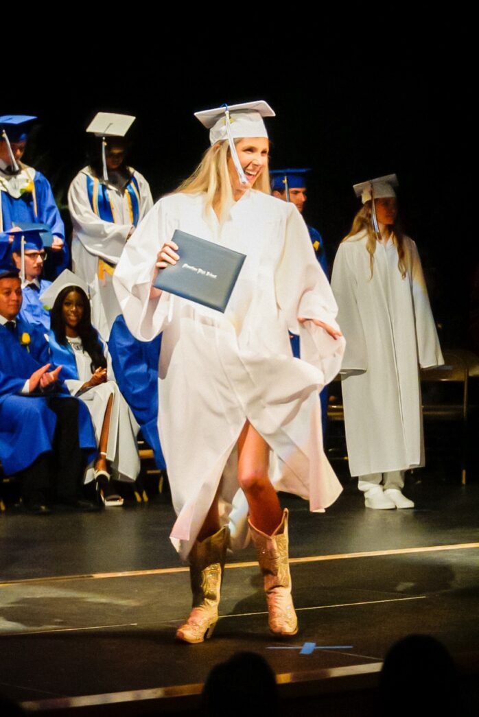 a woman in a graduation gown walking across a stage