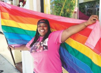 a woman in a pink shirt holding a rainbow flag