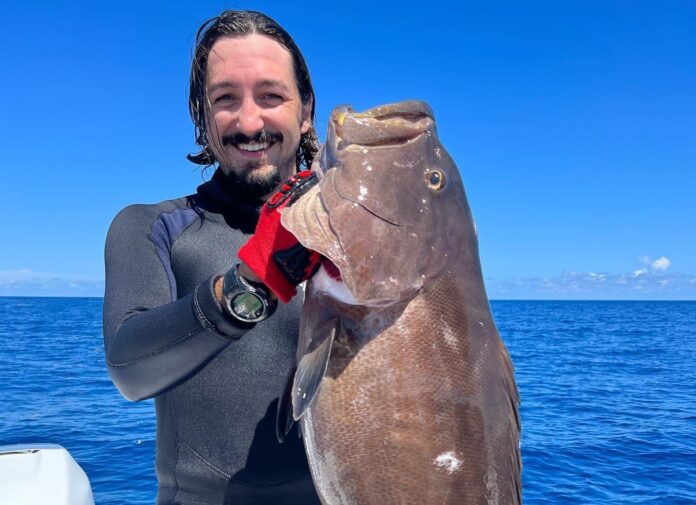 a man holding a large fish on a boat