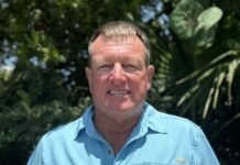 a man in a blue shirt standing in front of trees