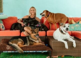 a woman sitting on a couch with three dogs