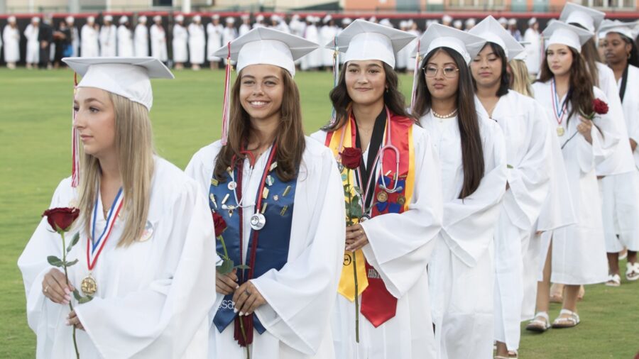 a group of women in graduation gowns standing on a field