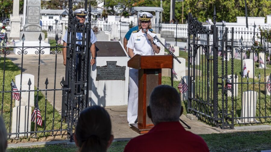 a man standing at a podium in front of a cemetery