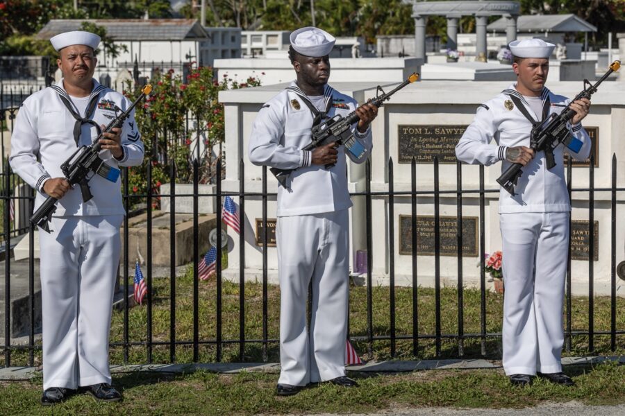 a group of men in white uniforms holding guns