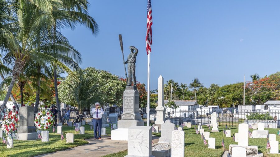 a man standing in front of a flag at a cemetery