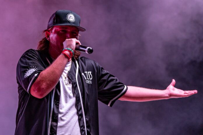 Mike Stack0502 a man with long hair and a baseball cap holding a microphone