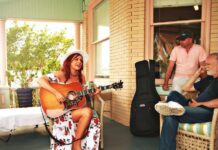 a woman sitting on a porch playing a guitar