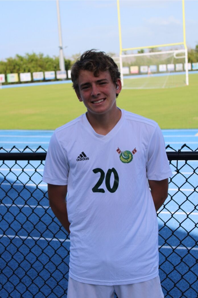 a man standing in front of a fence with a soccer ball