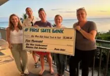 a group of people standing next to each other holding a check
