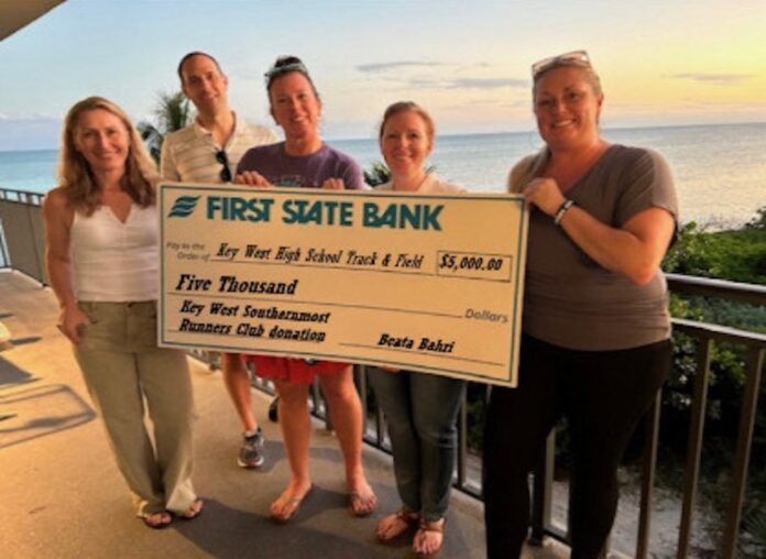 a group of people standing next to each other holding a check