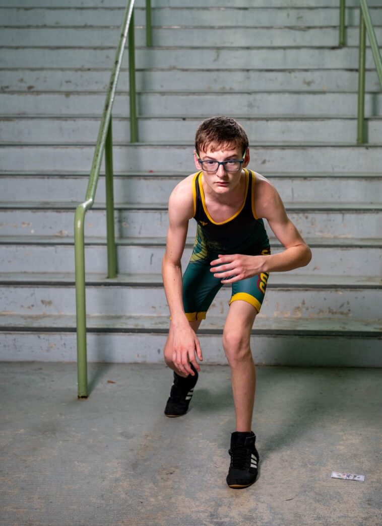 a man in a wrestling uniform squatting in front of a set of stairs
