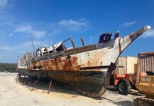 a rusted boat sitting on top of a sandy beach