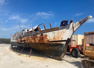 a rusted boat sitting on top of a sandy beach