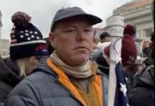 a man in a hat and scarf holding a flag